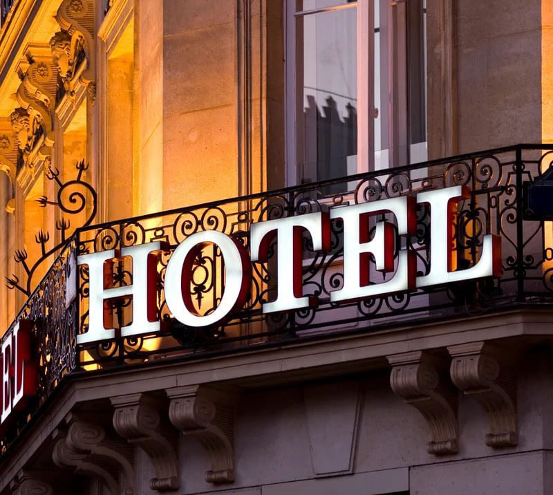 A hotel sign radiating light in the darkness, showcasing its welcoming presence as part of a travel package.