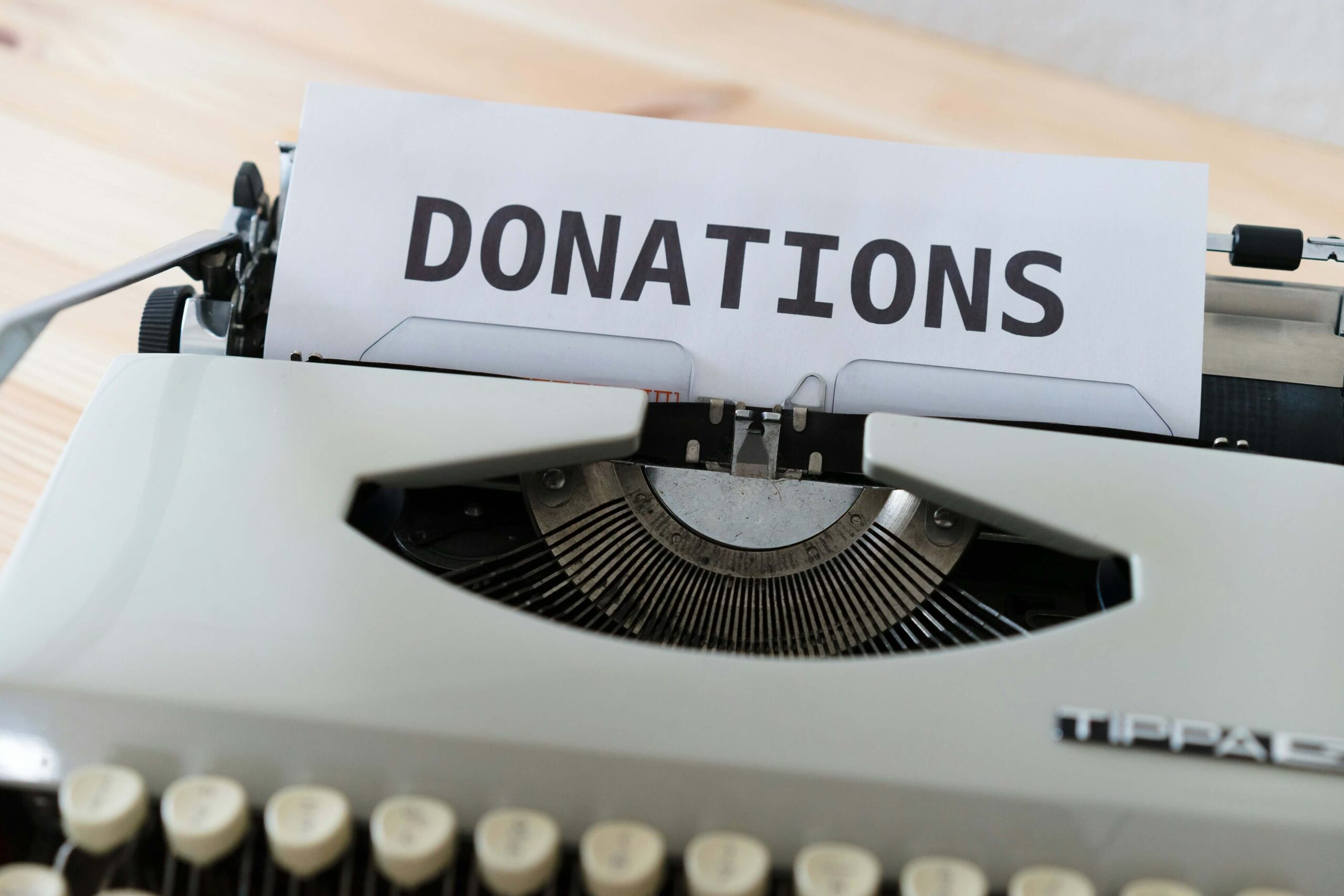 A vintage typewriter with a pile of donations placed on top, symbolizing support for a vacation-themed charity event.